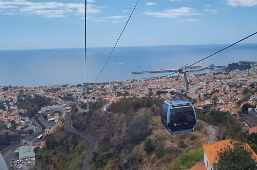 Cable car cabin descending over a coastal town and the sea