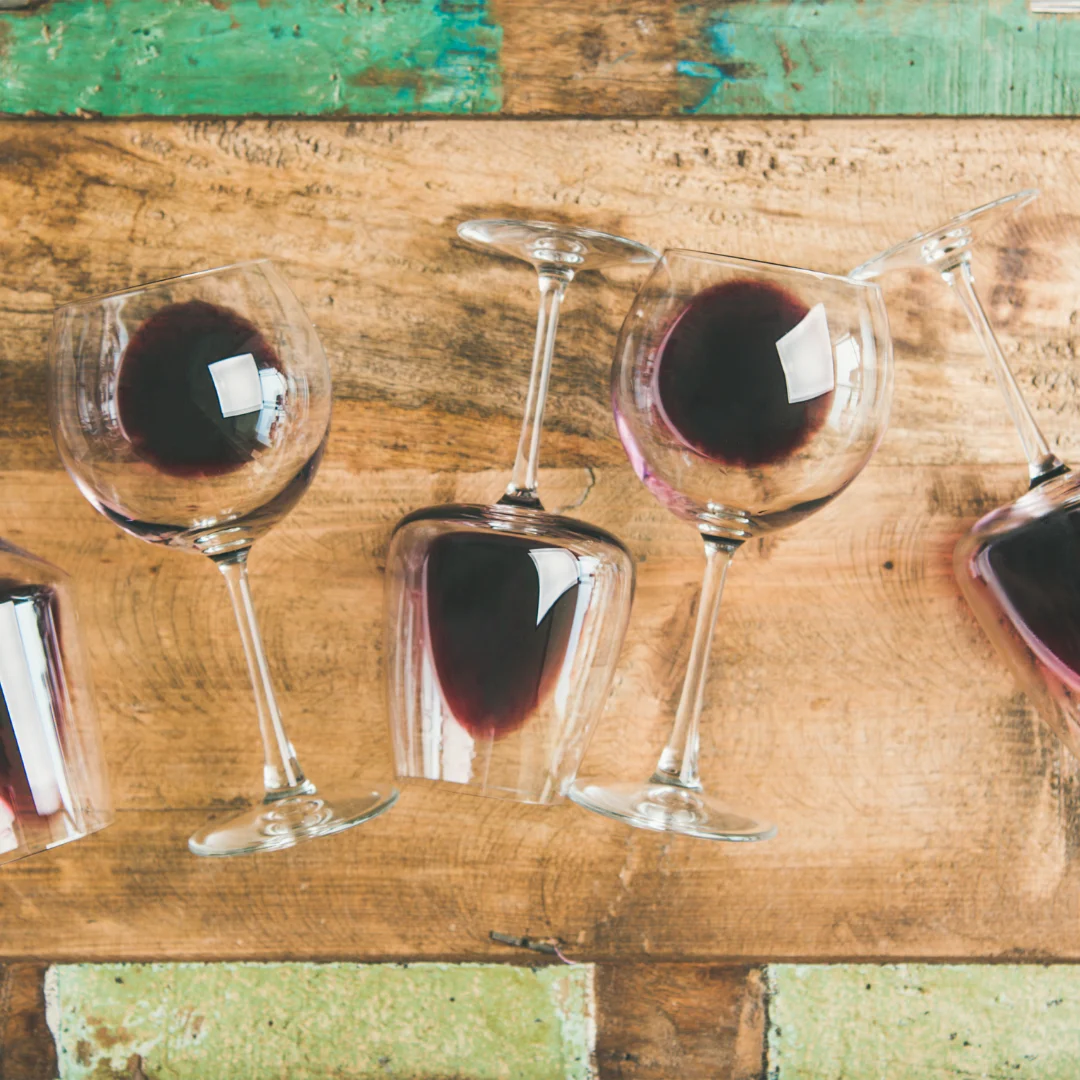 Glasses of red wine lying on a rustic wooden table