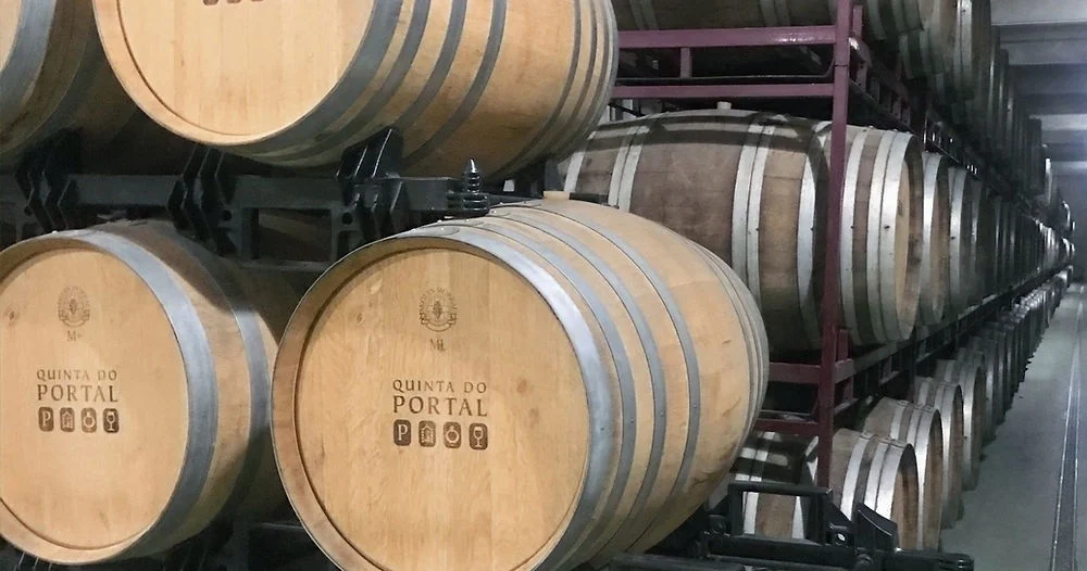Large oak barrels with a Quinta do Portal logo in a barrel hall