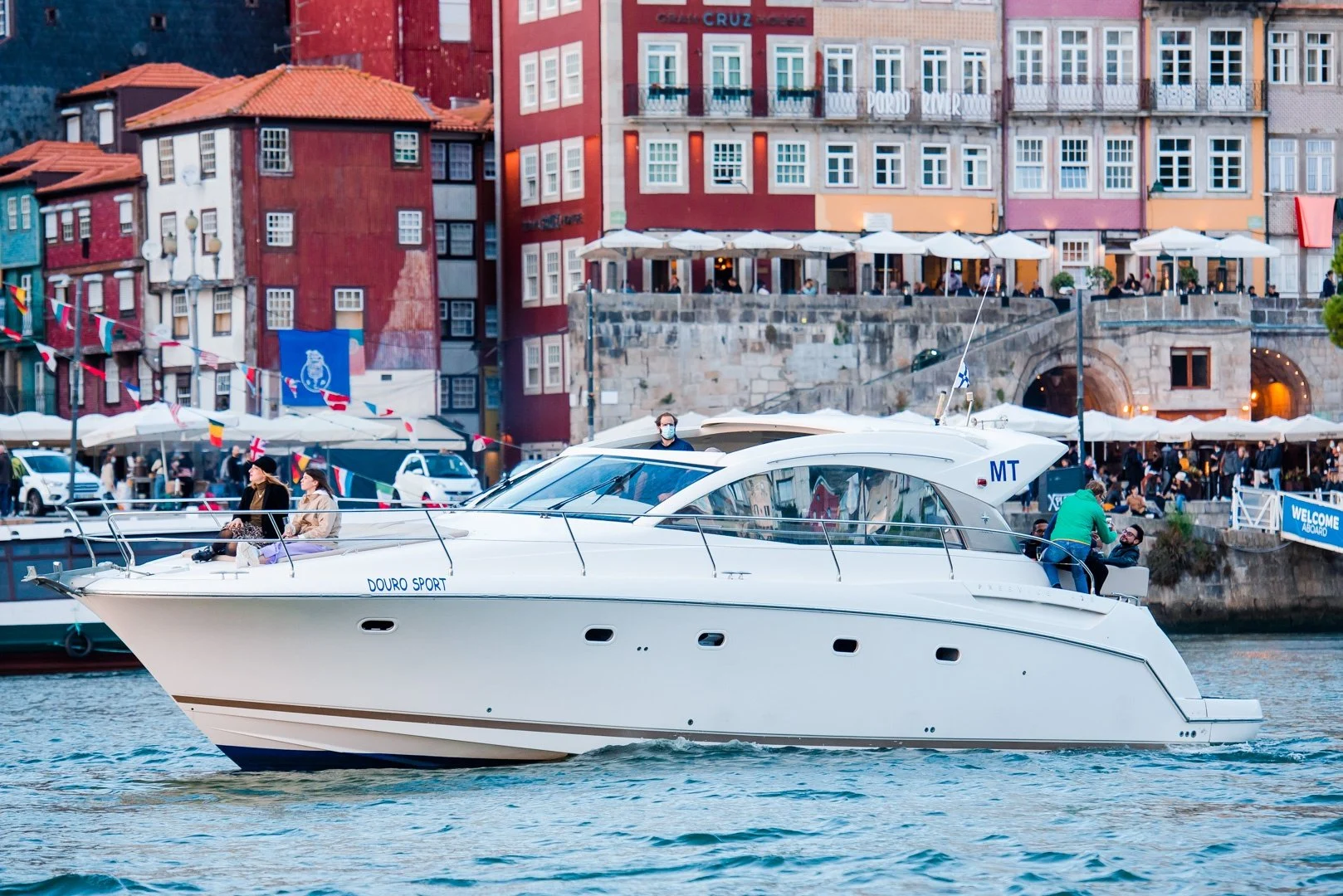 White motor yacht passing colourful riverfront buildings