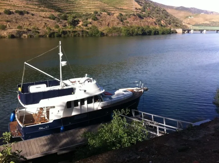 Blue yacht moored at a river bank among vineyard slopes