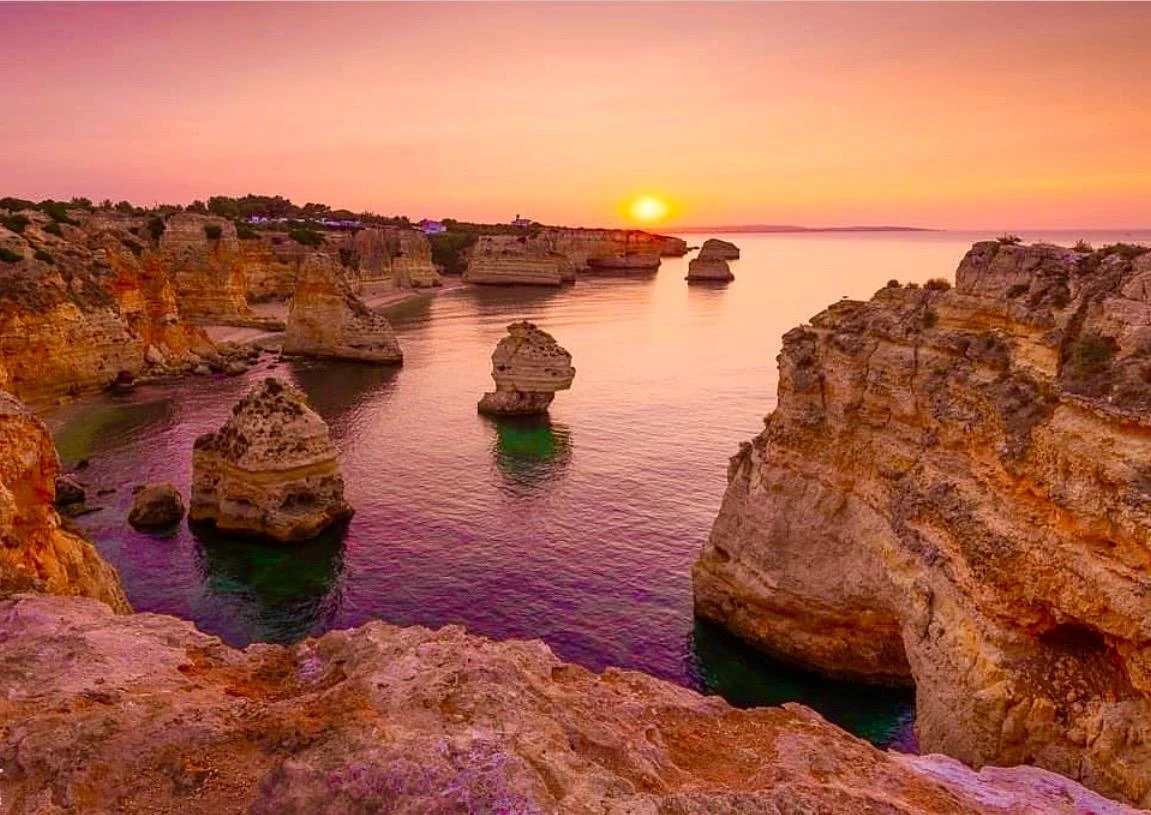 Sunrise glow over golden cliffs and rock stacks along the coast
