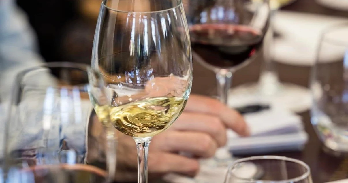 Glasses of red and white wine on a table with blurred people behind
