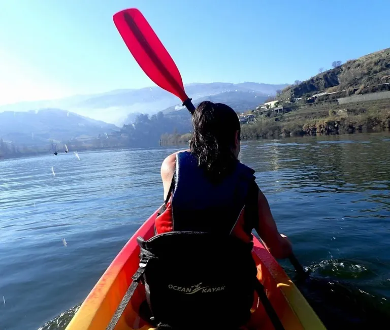 Kayaker paddling on a river towards forested hills