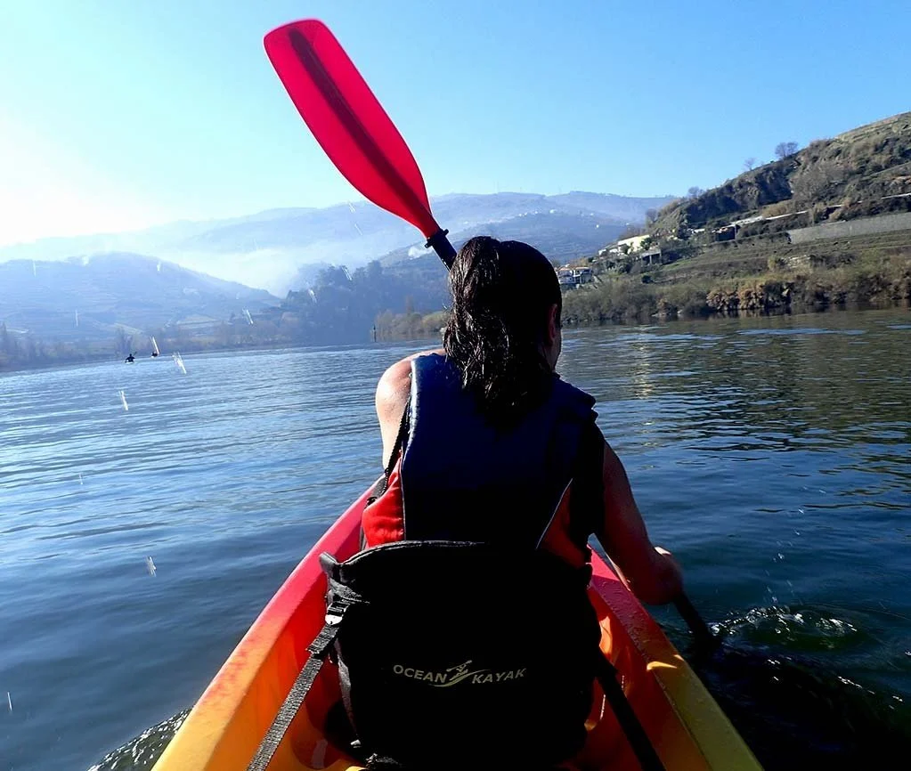 Kayaker paddling on a river towards forested hills