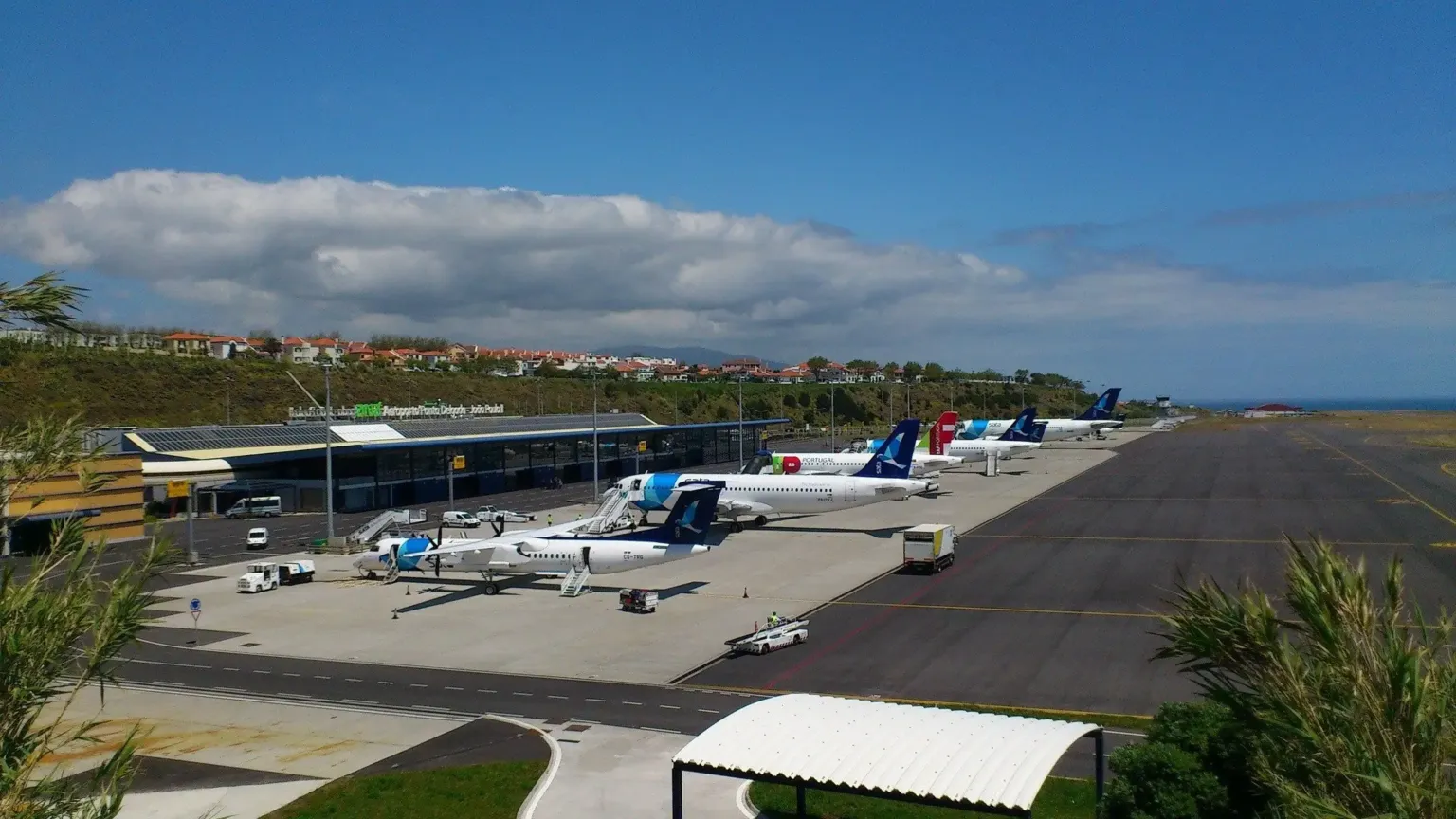 Airport apron with parked turboprop planes under a blue sky