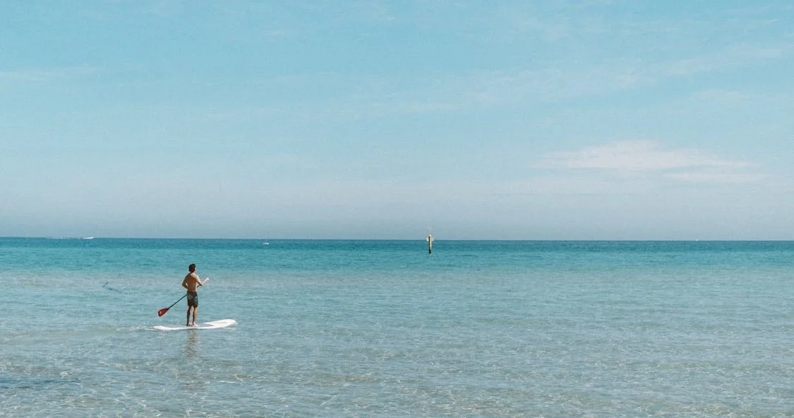 Paddleboarder distant sur une eau turquoise calme