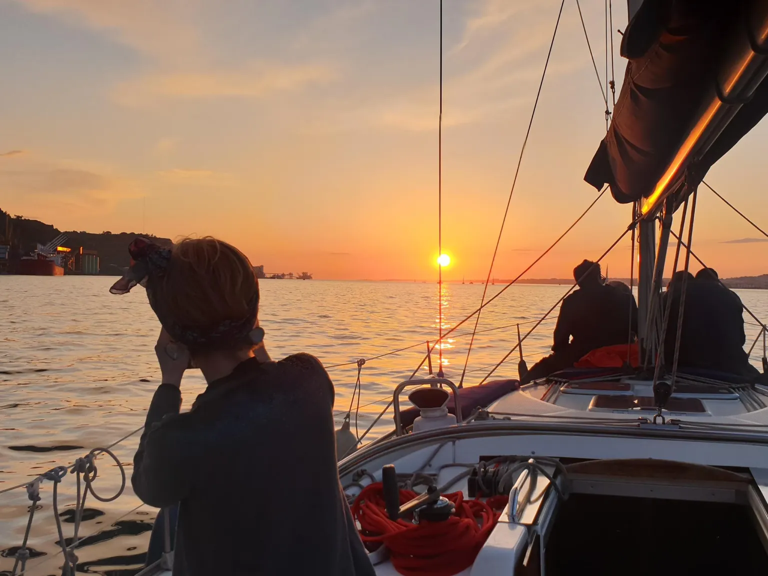 Silhouetted passengers on a sailboat at sunset