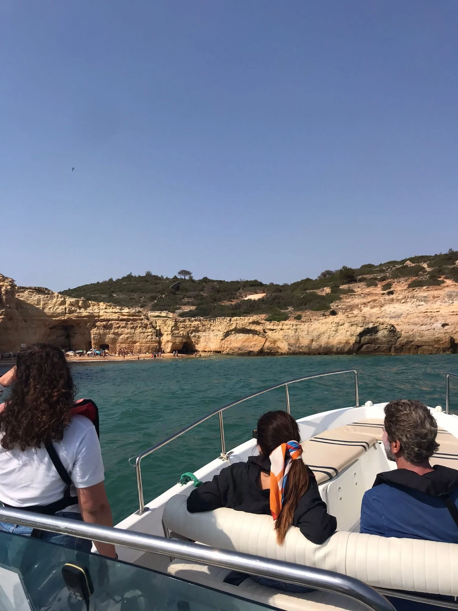 Passengers on a boat looking at cliffs along the coast