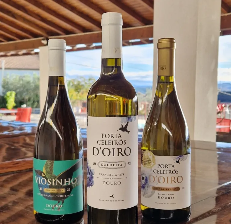 Three bottles of white wine on a table, with the valley behind