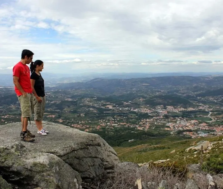 Couple standing on a rocky outcrop looking over a valley and town