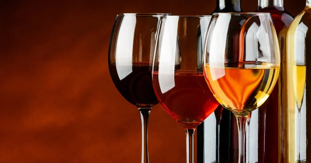 Glasses of red, rosé and white wine against an orange background