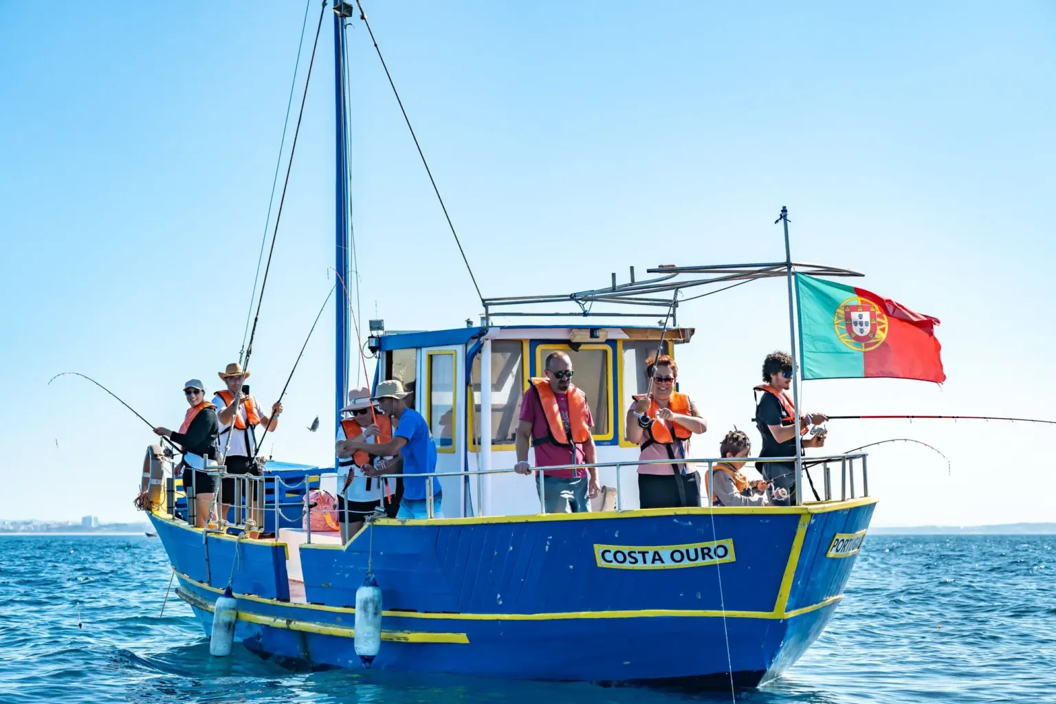 Blue fishing boat with a Portuguese flag and anglers on deck