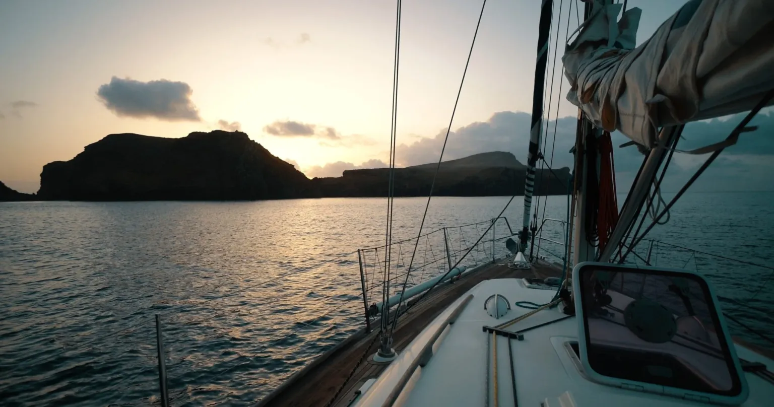 Island silhouette at sunrise seen from a sailboat deck