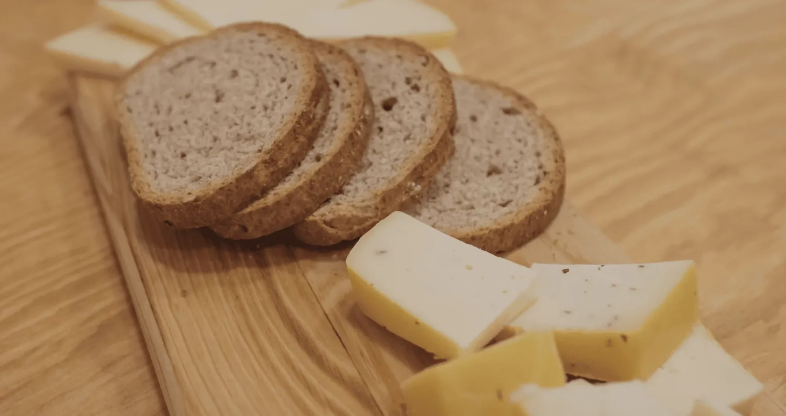 Sliced bread and cheeses on a wooden board