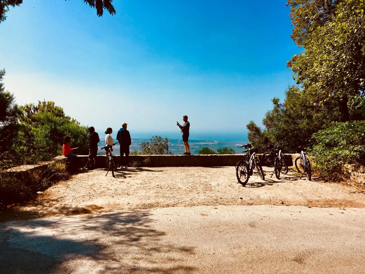 E-bikes parked at a coastal viewpoint with visitors looking over the sea