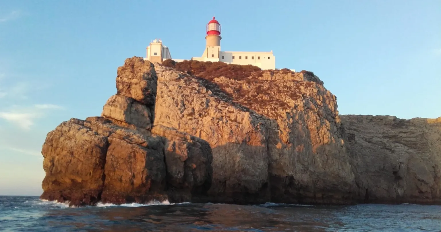 Rocky headland topped with a red-and-white lighthouse