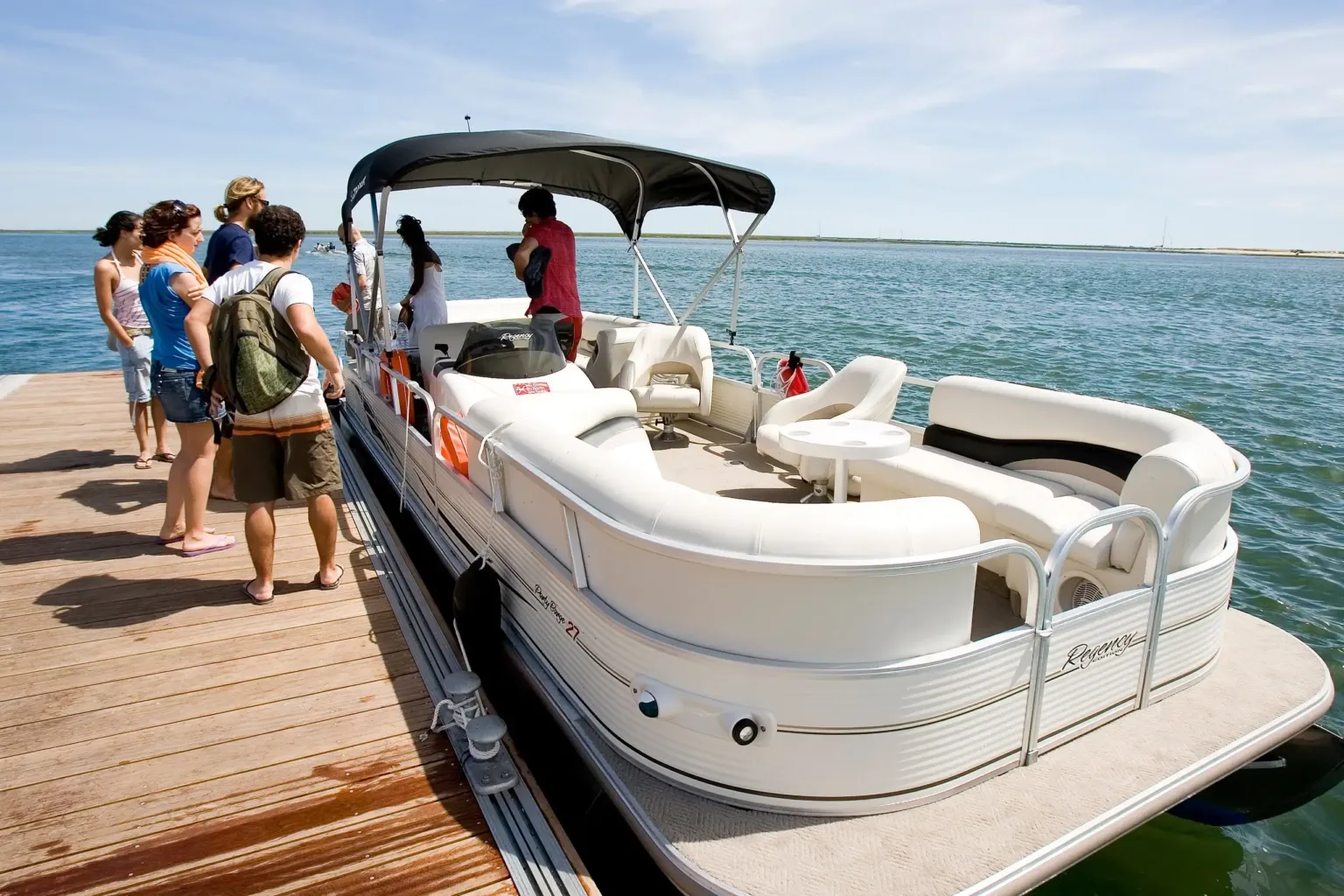 Guests boarding a pontoon boat at a wooden jetty