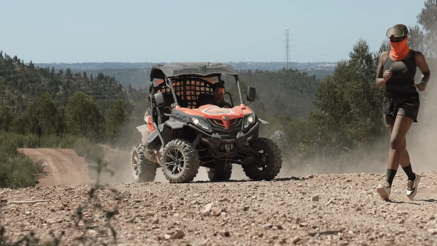 Off-road buggy driving along a dusty gravel track through wooded hills