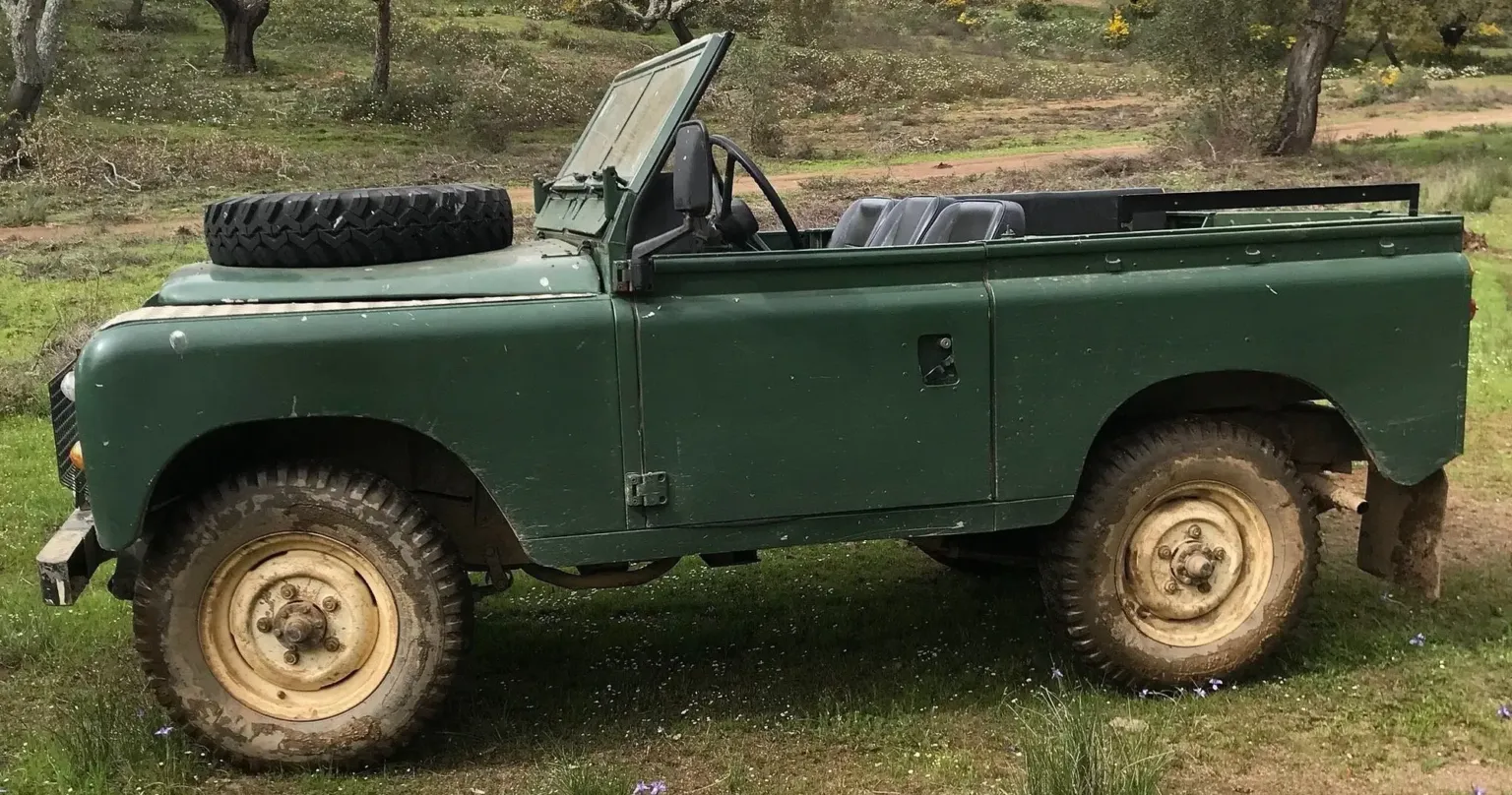 Grüner Oldtimer-Land-Rover auf einem Feldweg auf dem Land