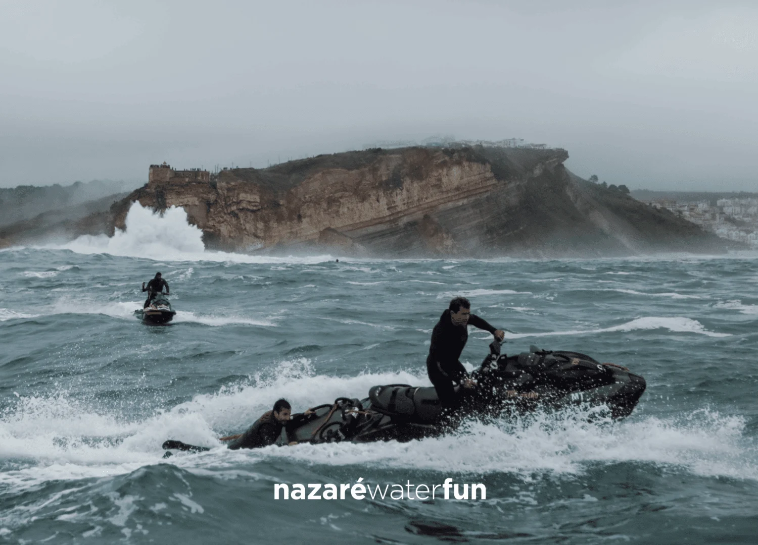 Rider on a jet ski off a stormy rocky coast, with a Nazaré Water Fun logo