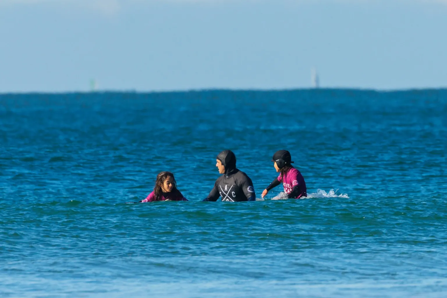 Surfers and a student floating in calm blue water