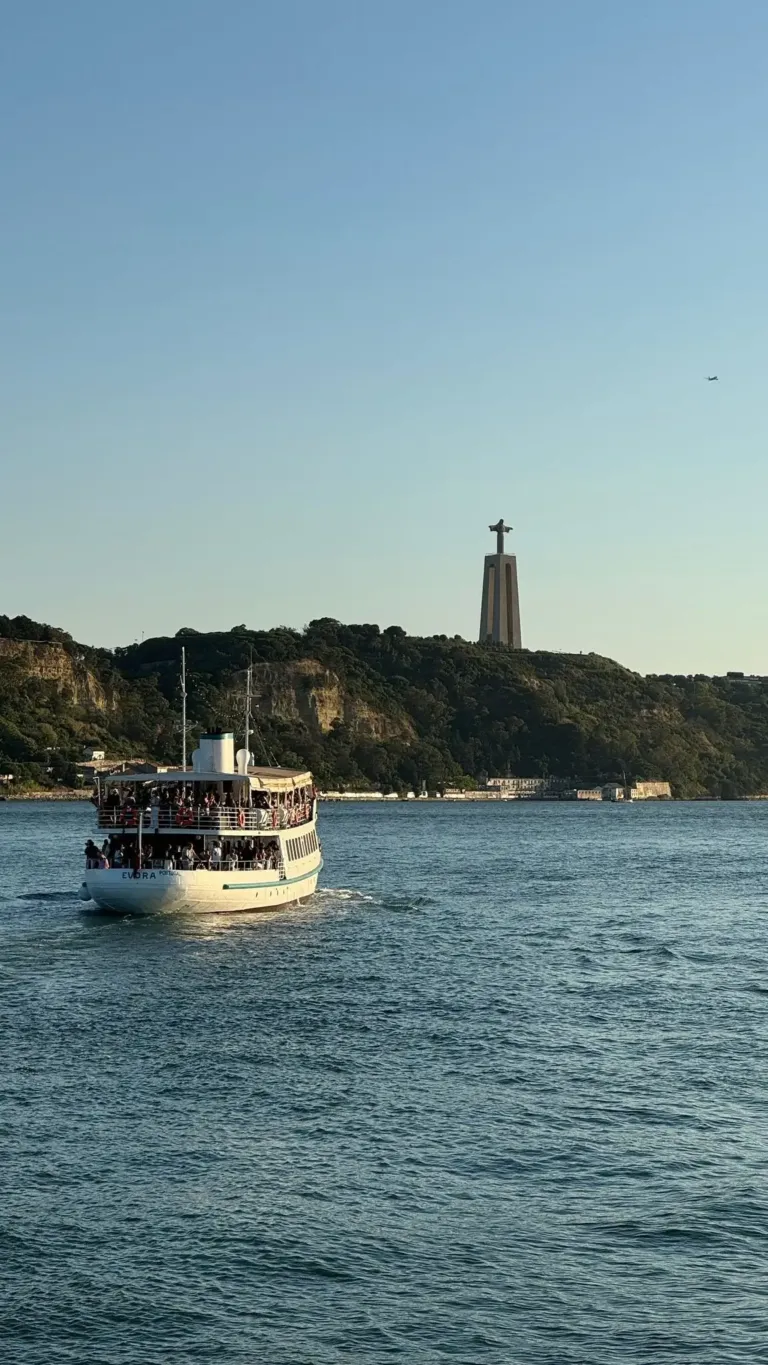 Passenger boat on the river below a hilltop statue of Christ