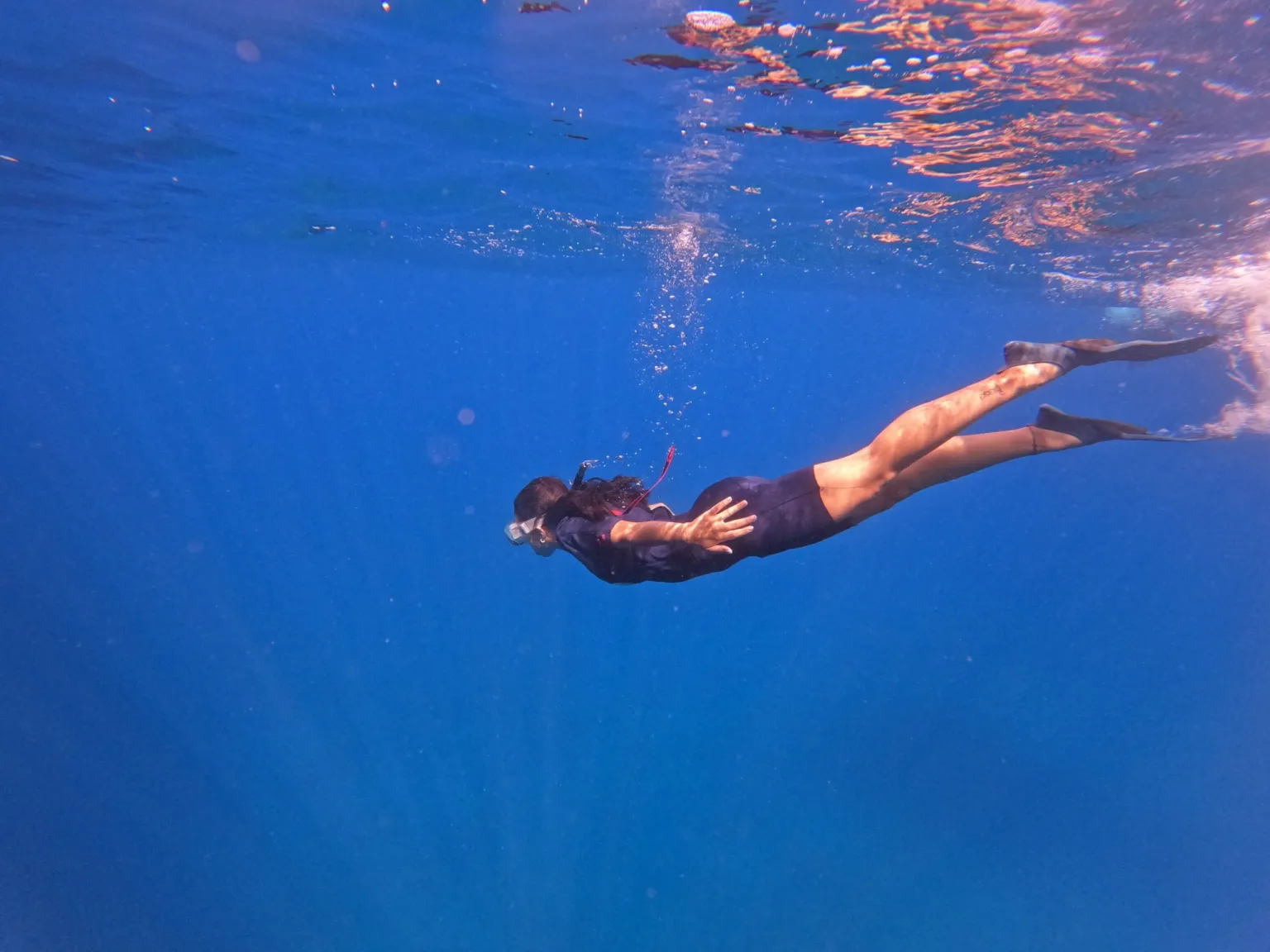 Free diver swimming underwater in deep blue water