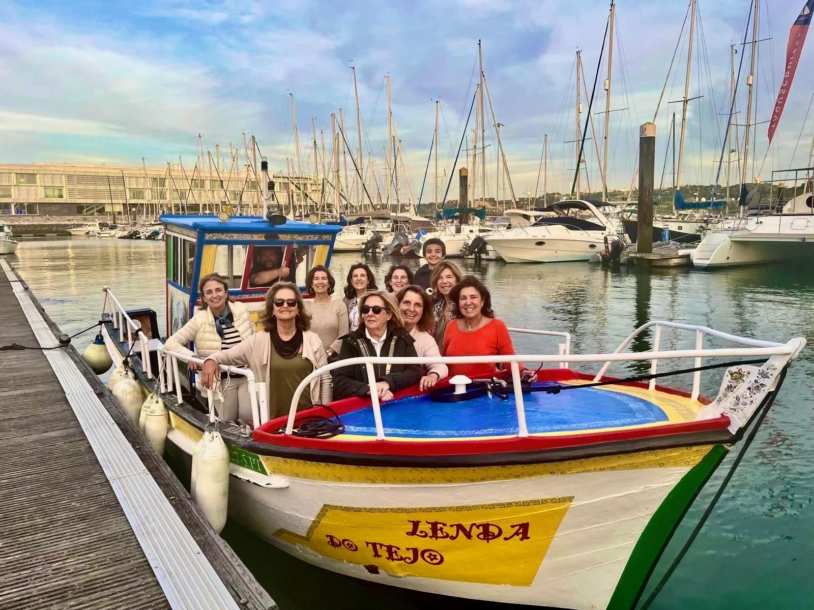 Women posing on a traditional painted boat moored in a marina