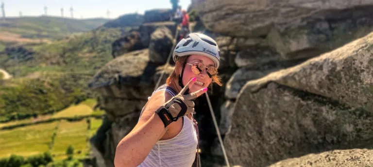 Smiling climber in a helmet on a rock face during a via ferrata