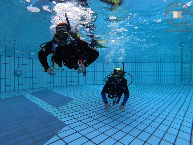 Divers practising underwater in a tiled pool