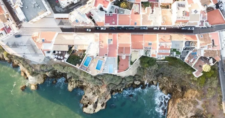 Aerial view of a seaside town's rooftops and a rocky cliff coast