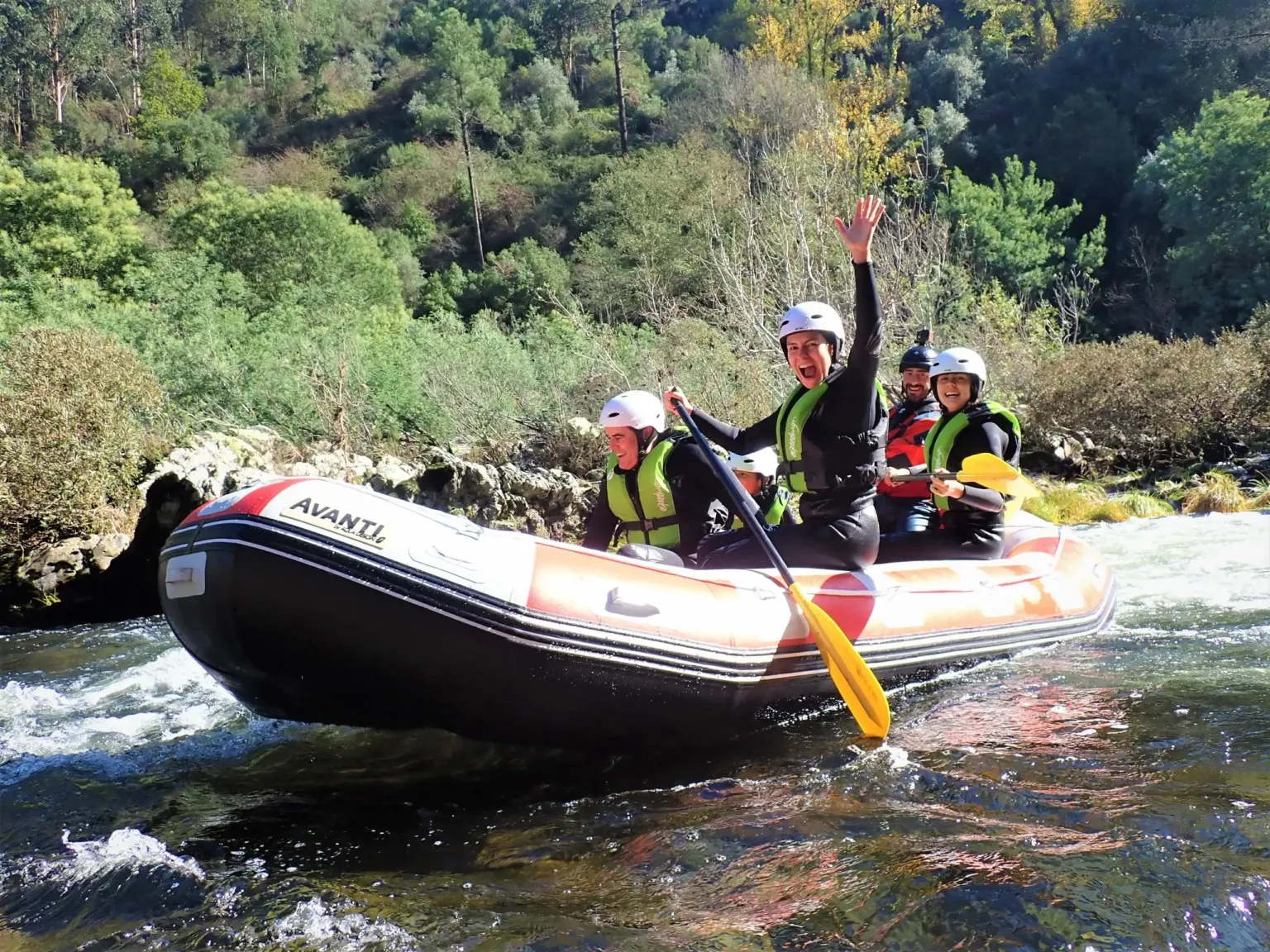 Raftingbemanning met helmen die zwaait als de raft een stroomversnelling neemt