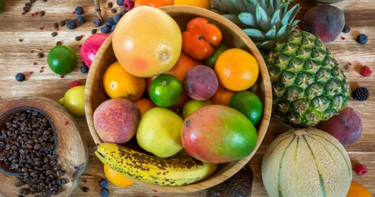 Bowl of tropical fruit beside coffee beans