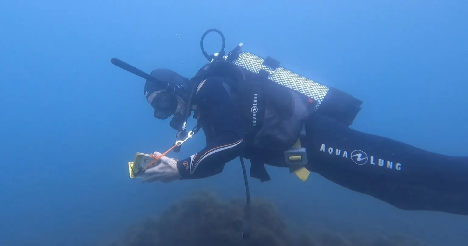 Diver checking a gauge on a rocky seabed