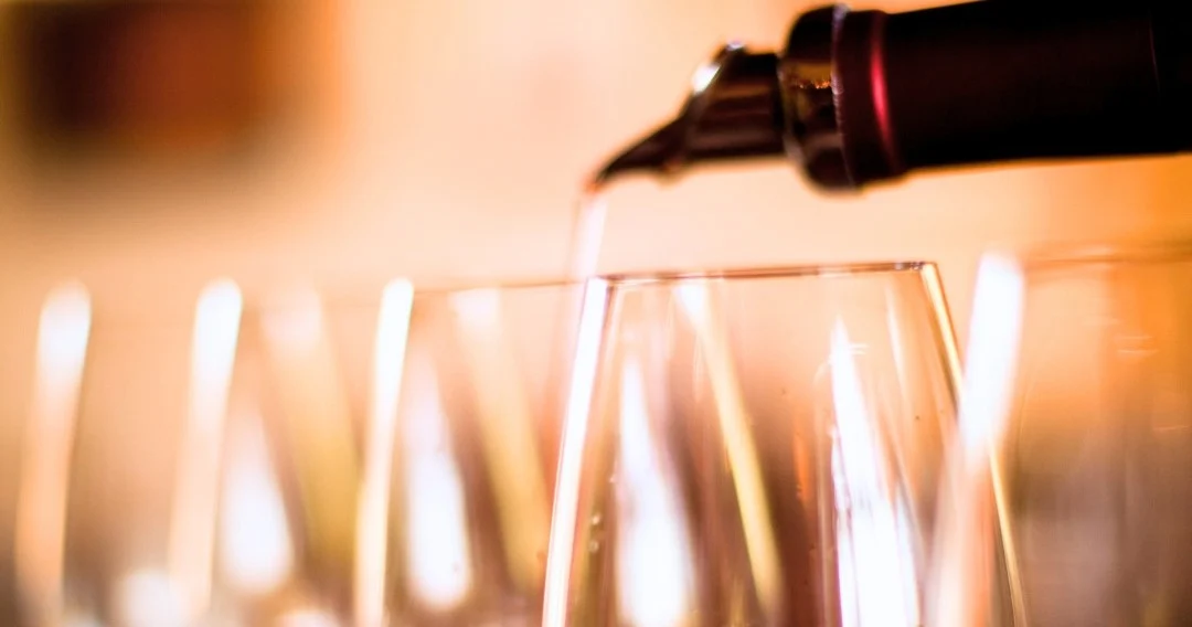 Wine being poured into glasses with blurred lights behind