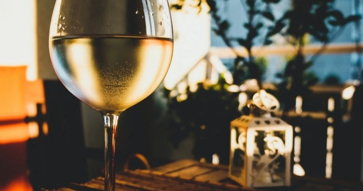 Glass of white wine on a table with a lantern beside it