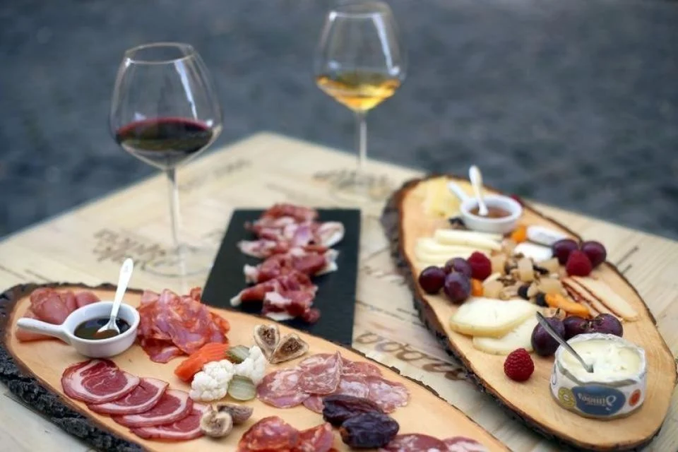 Boards of cured meats, cheeses and preserves with glasses of wine
