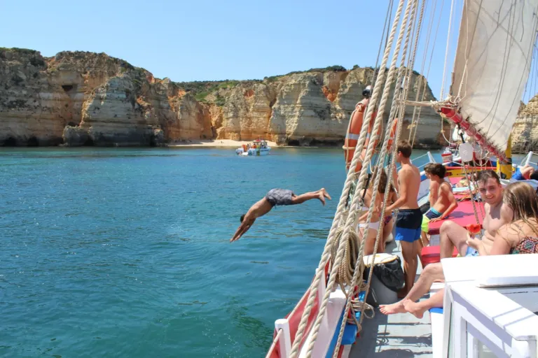 Sailing boat anchored off a cove as a guest dives into the sea