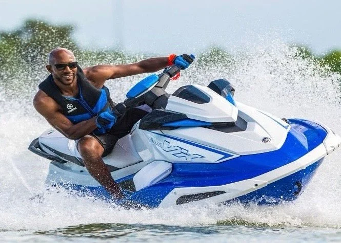 Man riding a blue-and-white jet ski through spray