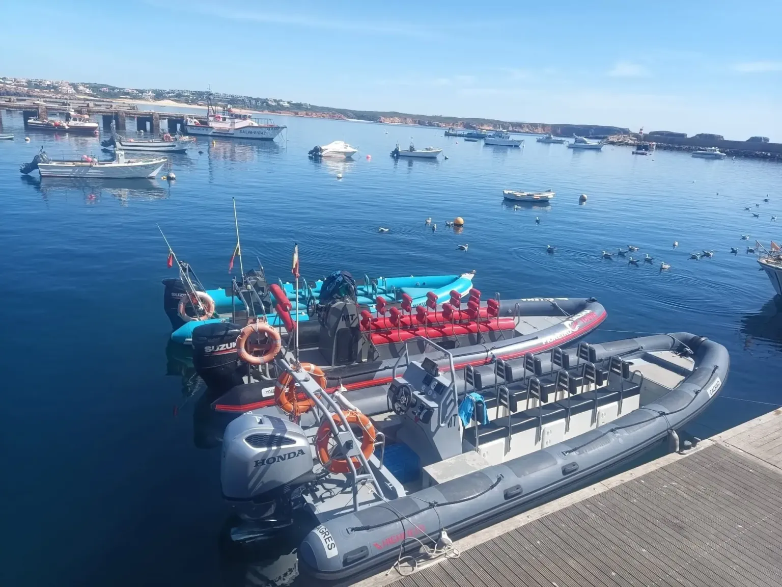 Rigid inflatable boats moored at a quay in a busy harbour