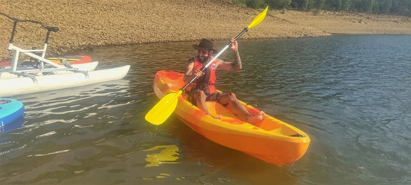 Person in an orange kayak paddling on a calm lake
