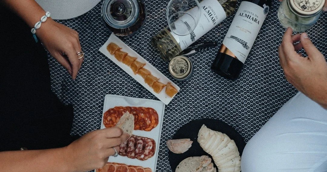 Hands sharing cured meats and wine over a table