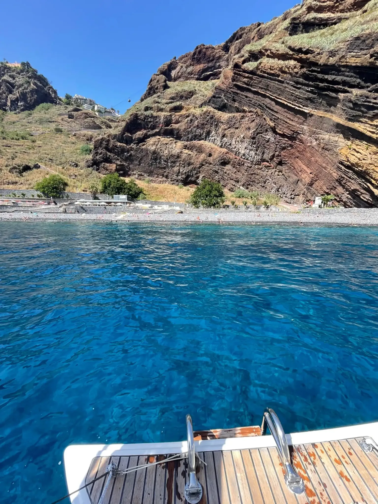 Sea cliffs of banded rock above clear blue water
