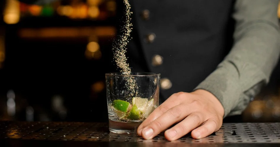 Bartender squeezing lime into a glass at a bar