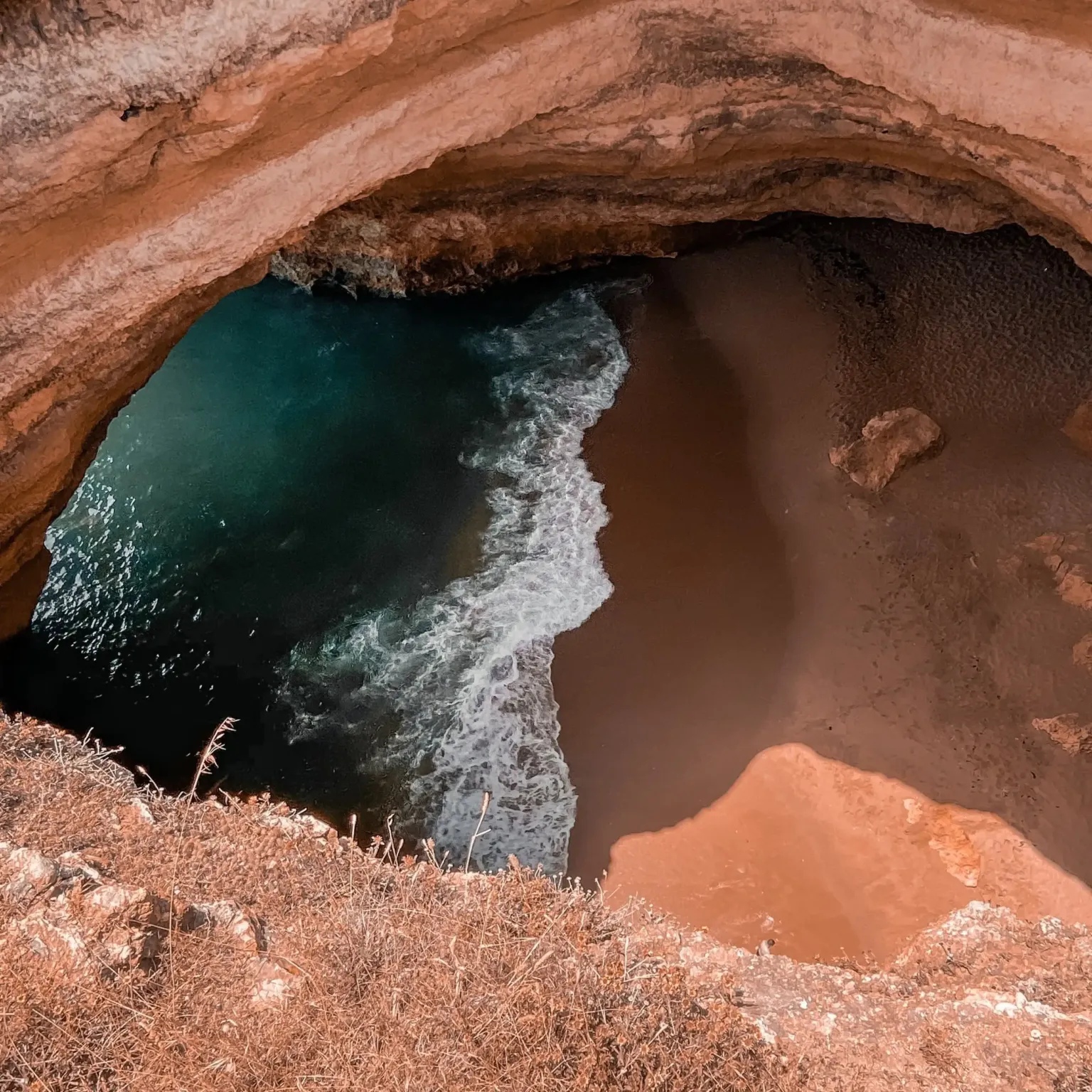 Aerial view of a sea cave opening above the surf