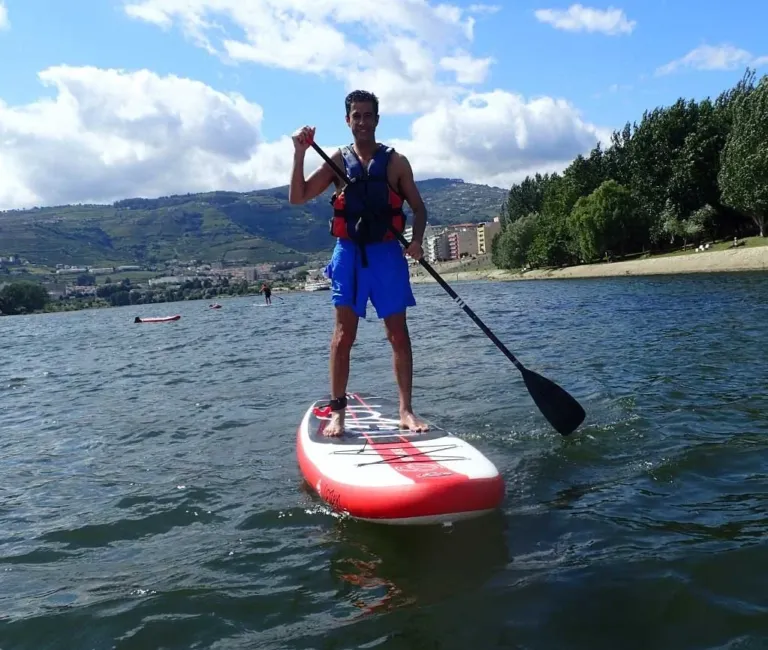 Paddleboarder with a paddle on a river beside a town
