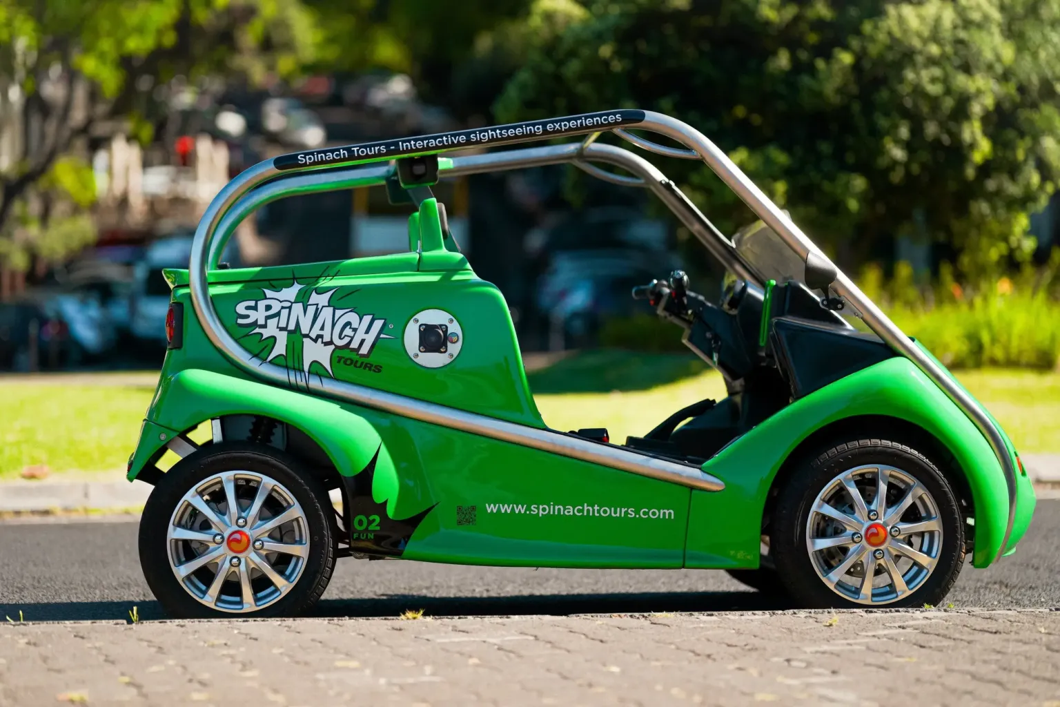 Side view of a green open-top electric buggy with a roll bar