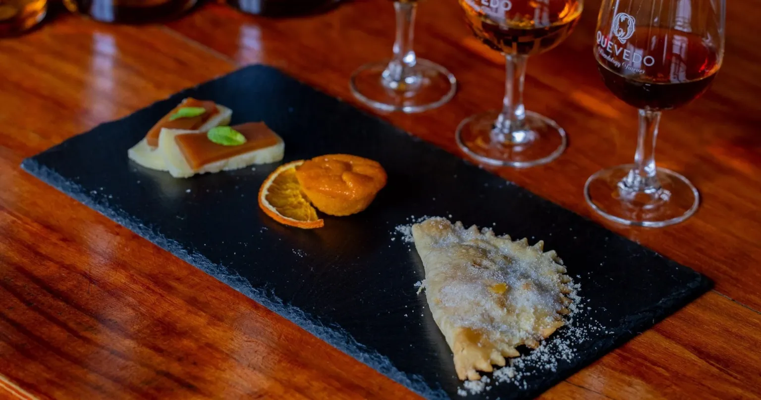 Slate board of pastries beside glasses of port