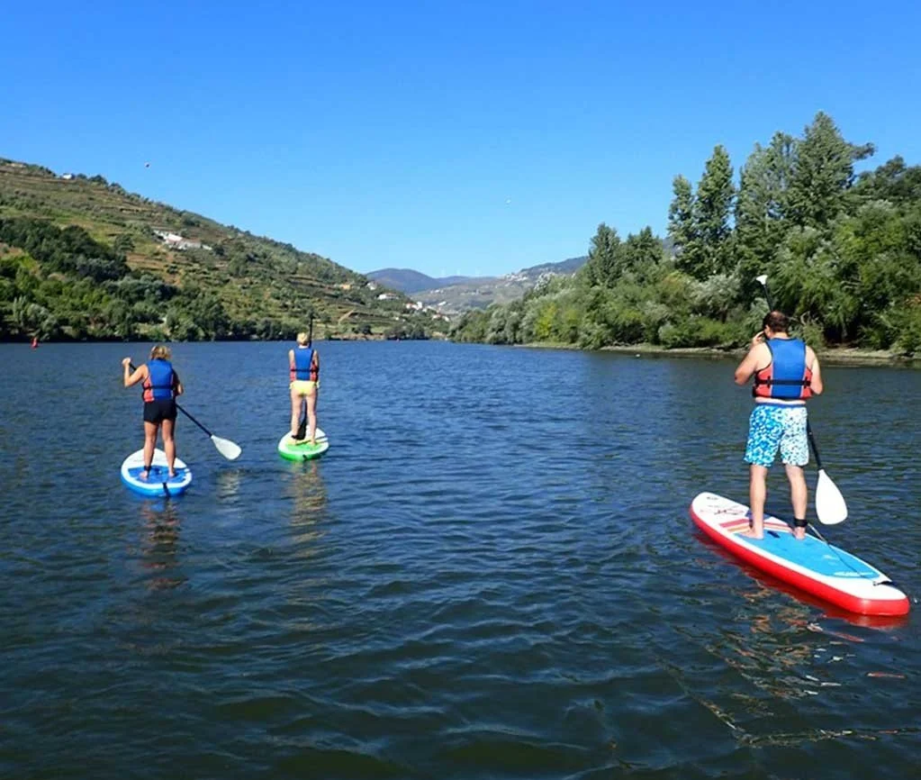 Paddleboarders on a calm river between green hills